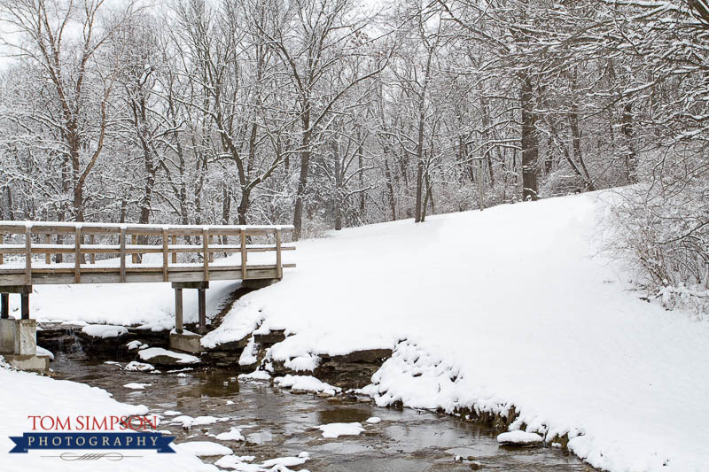 water running under wood bridge during winter